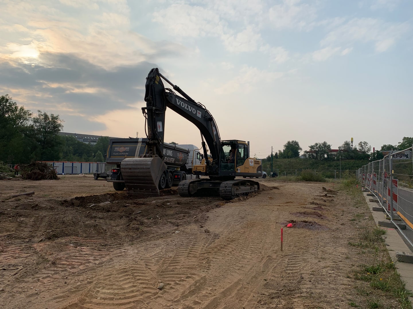 Aushubüberwachung_Bagger auf Räumstelle Aushub durch einen Bagger auf einer Räumstelle. Rechts Bohrlöcher einer Tiefensondierung.