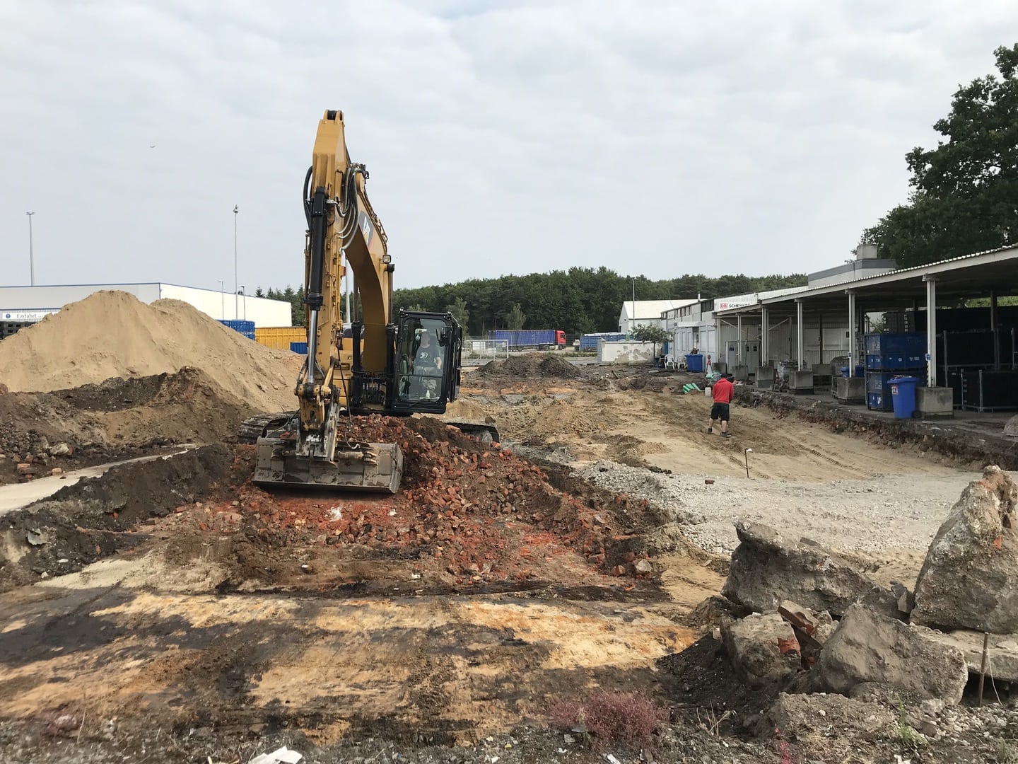 Baufeldberäumung_Bagger Aushubüberwachung, Kampfmittelräumung auf einer Fläche. Ein Bagger räumt die Fläche frei.